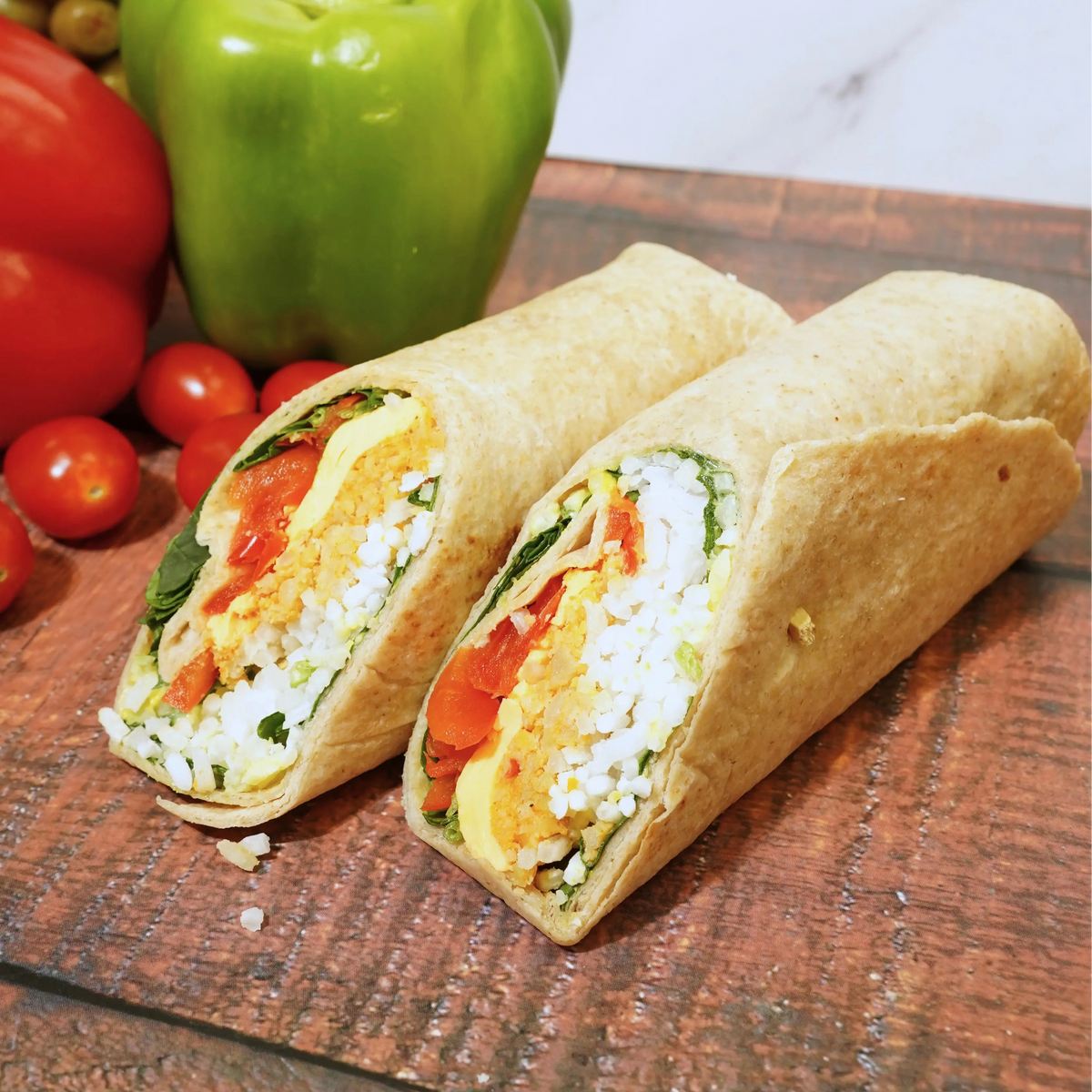 Wrap with vegetables on a wooden board with peppers and olives in the background